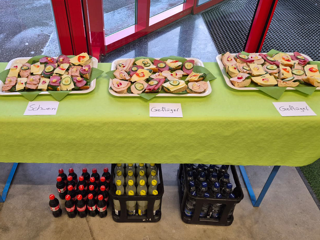 Belegte Br&ouml;tchen mit K&auml;se, sowie Wurst vom Gefl&uuml;gel und Schwein. Unter dem Tisch Cola und Wasser.