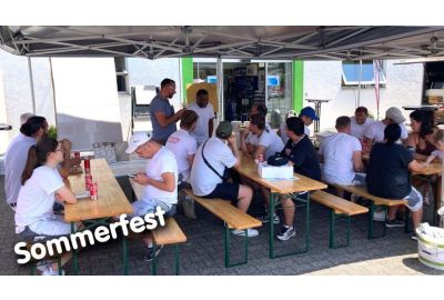Maler sitzen auf Bierzeltgarnituren unter einem Pavillon von der Filiale Darmstadt