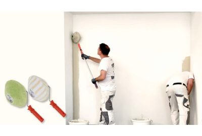 Maler walzt eine Ecke mit dem Maler-Jumbo Eckenroller, der andere in der anderen Ecke mit einer Heizkörperwalze und Heizkörperpinsel - Beide Maler-Jumbo-Eckenroller sind abgebildet