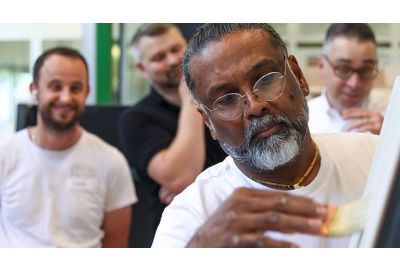 Dilip arbeitet konzentriert und die Schulungsteilnehmer schauen zu