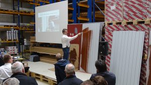 Referent von Rustoleum beschichtet im weißen Hemd ein Blech mit braunem Noxyde