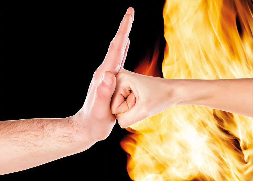 Faust schlägt gegen eine Hand - Hintergrund ist schwarz mit Feuer