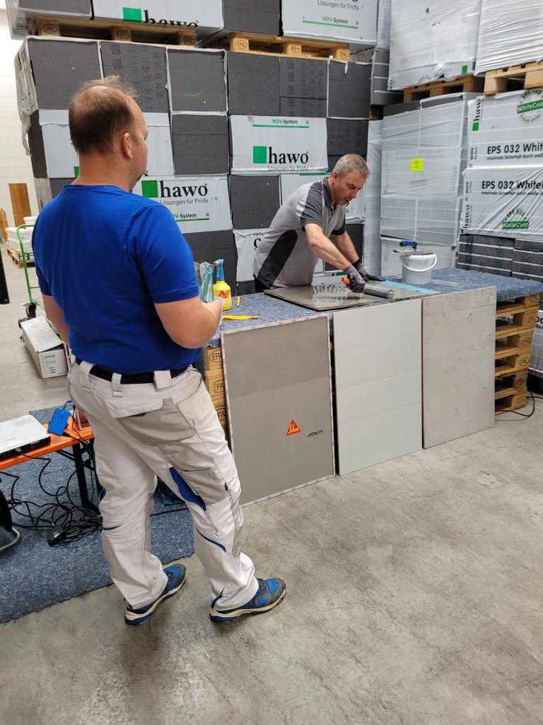 Sika Anwendungstechniker beschichte eine Musterpatte - Teilnehmer schaut zu