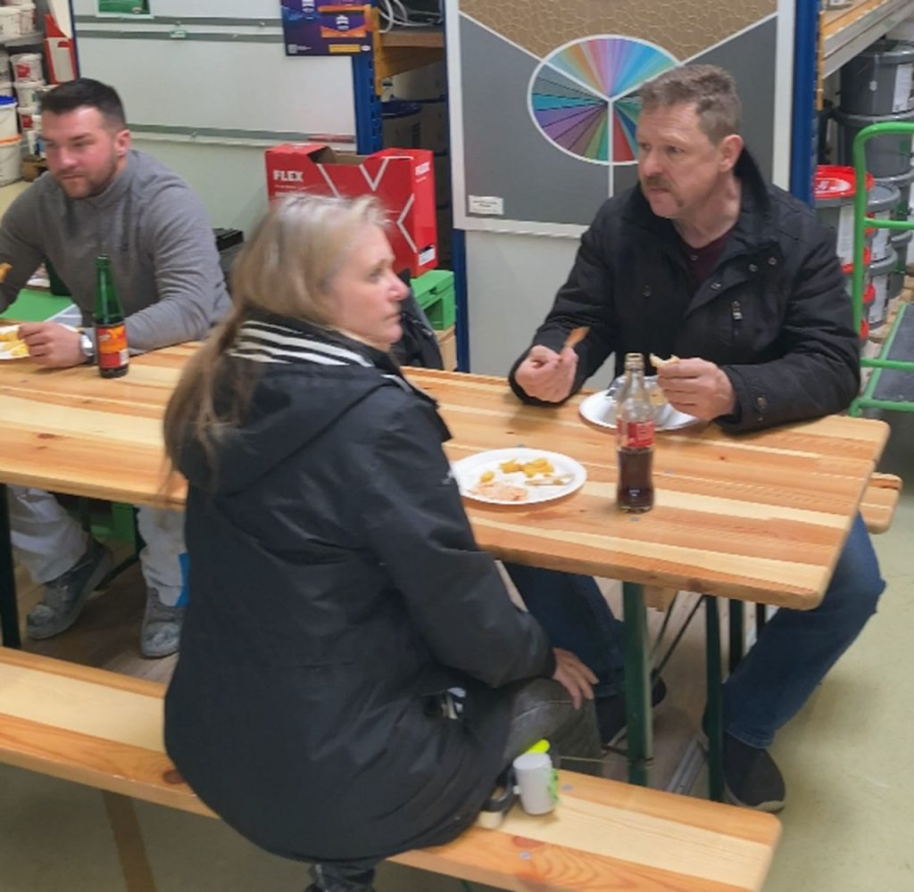 3 Kunden an der Bierzeltgarnitur essen und trinken