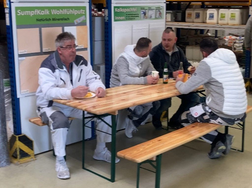 4 Kunden an der Bierzeltgarnitur essen und trinken