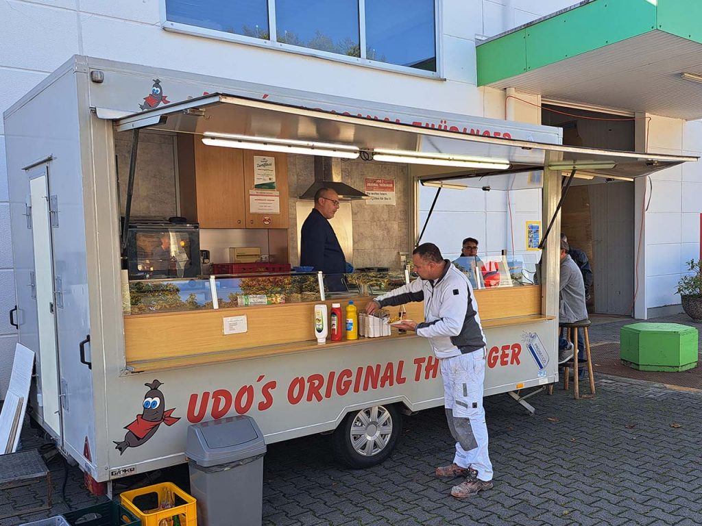 Udo's Original Thüringer - der Imbisswagen mit Udo und einem Kunden, der sich sein Essen holt