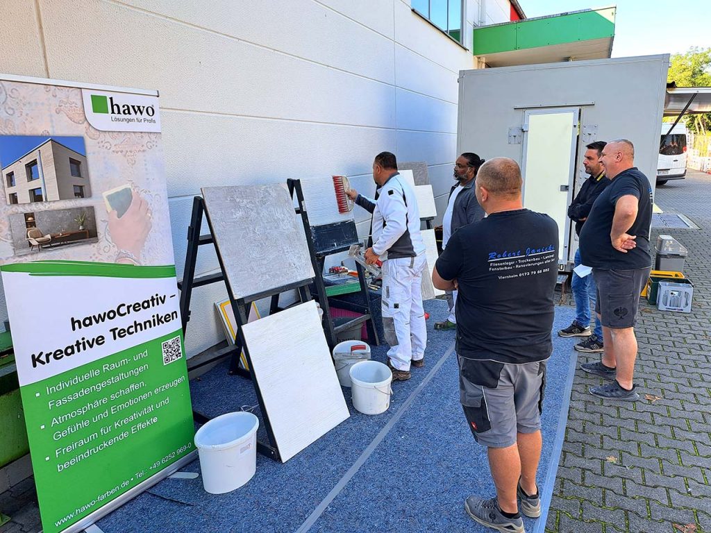 Im Außenbereich hat Dilip seinen Kreativplatz mit Staffeleien eingerichtet - ein Kunde erstellt eine Besenstrich-Musterplatte