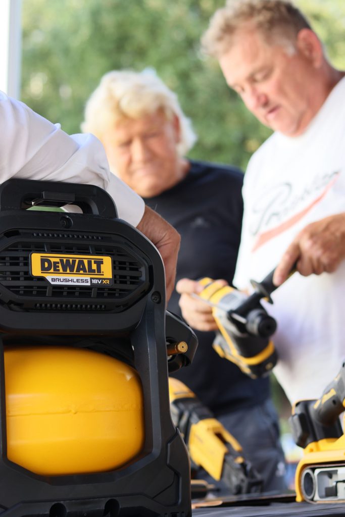 Detailaufnahme eines DeWALT Kompressor - im Hintergrund zwei Kunden die sich etwas anschauen - mit Tiefenschärfe