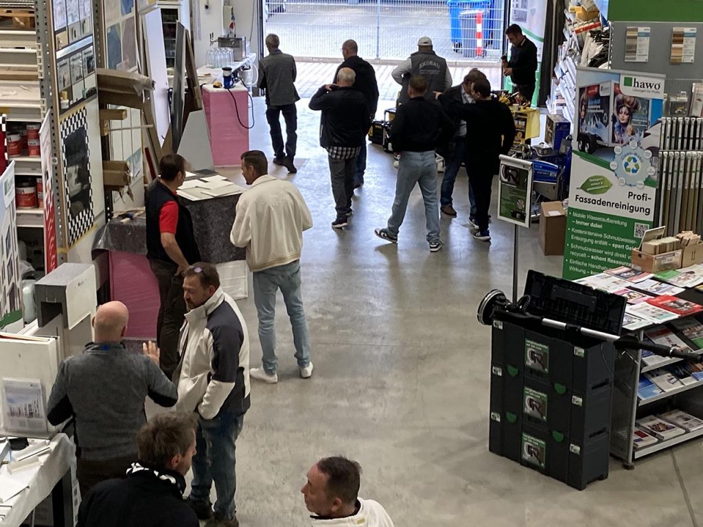 Foto von der ersten Etage in den Verkaufsraum - Kunden informieren sich an den Ständen
