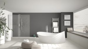moderenes, lichtdurchflutetes Bad mit einer freidstehenden Badewanne und einer dunkelgrauen Wand