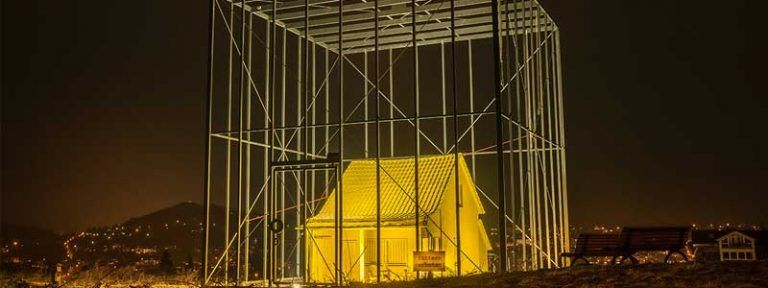 Das bedrohte Haus von Andreas Sarow - Haus beleuchtet im Käfig