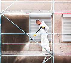Mann auf dem Gerüst beim Reinigen einer extrem schmutzigen Fassade