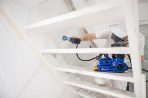 Mann mit Atemschutzmaske lackiert eine Treppe in weiß mit der Graco Ultra-QuickShot