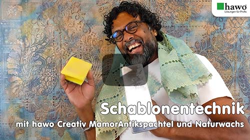 Titelbild des kompletten YouTube-Videos. Dilip steht vor seiner fertigen Wand und lacht fröhlich. Er hat die Italia-Schablonen um den Hals und in den Händen einen Schwam und eine venezianische Kelle